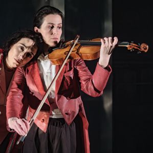 En kvinna spelar violin och en annan kvinna lutar huvudet mot hennes axel