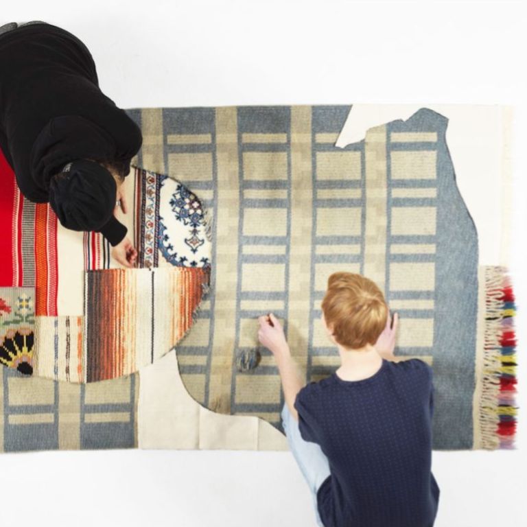 Två konstnärer som sitter på ett golv och arbetar sett uppifrån